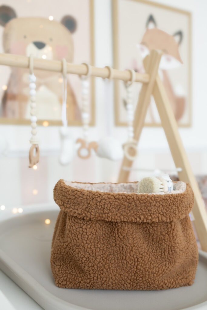 selbstgenähtes Utensilo aus braunem Teddystoff auf einem Wickeltisch, gefüllt mit Windeln.