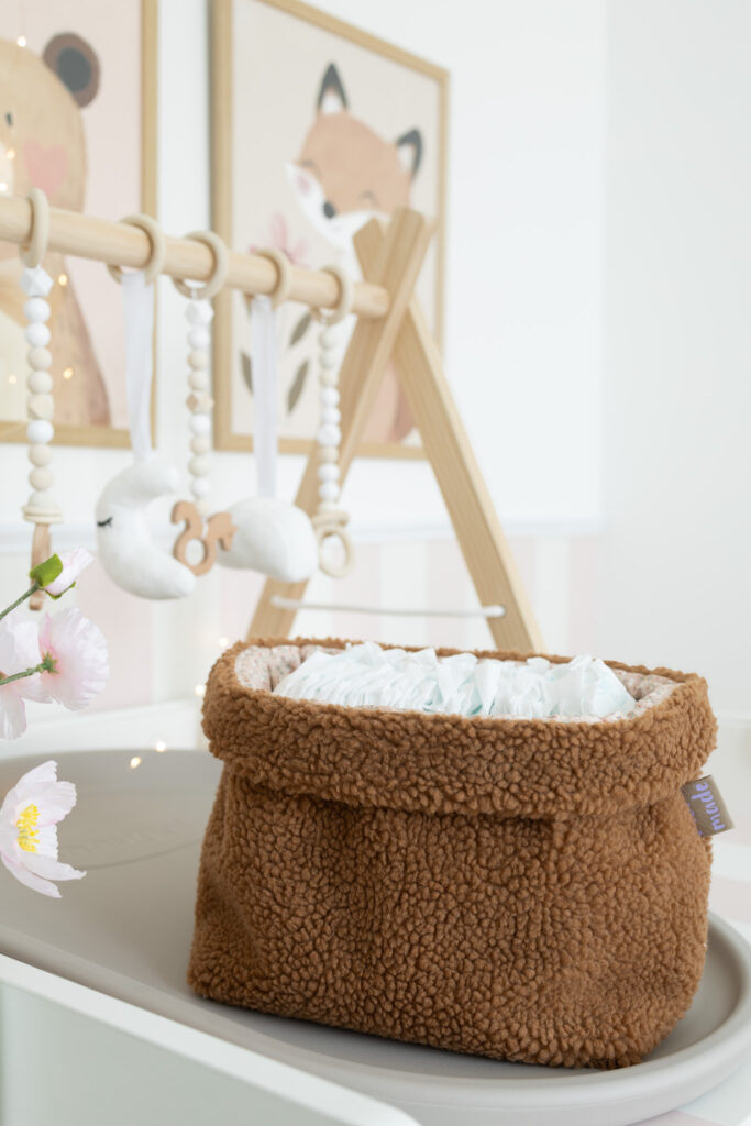 selbstgenähtes Utensilo aus braunem Teddystoff auf einem Wickeltisch, gefüllt mit Windeln.