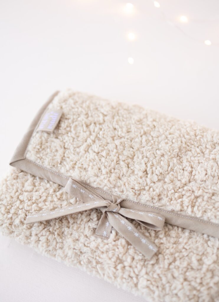 Nahaufnahme faltbare Wickelunterlage aus Teddystoff mit Schleifen nach der Nähanleitung von Make It Yours The Label